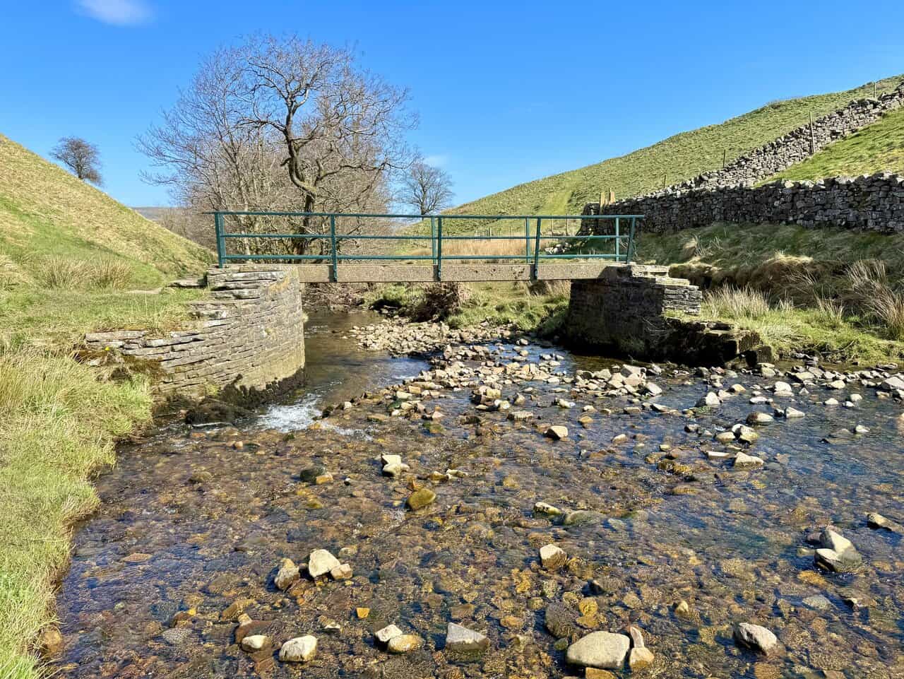 A small footbridge crossing the picturesque stream beyond Aysgill Force in a peaceful rural setting.