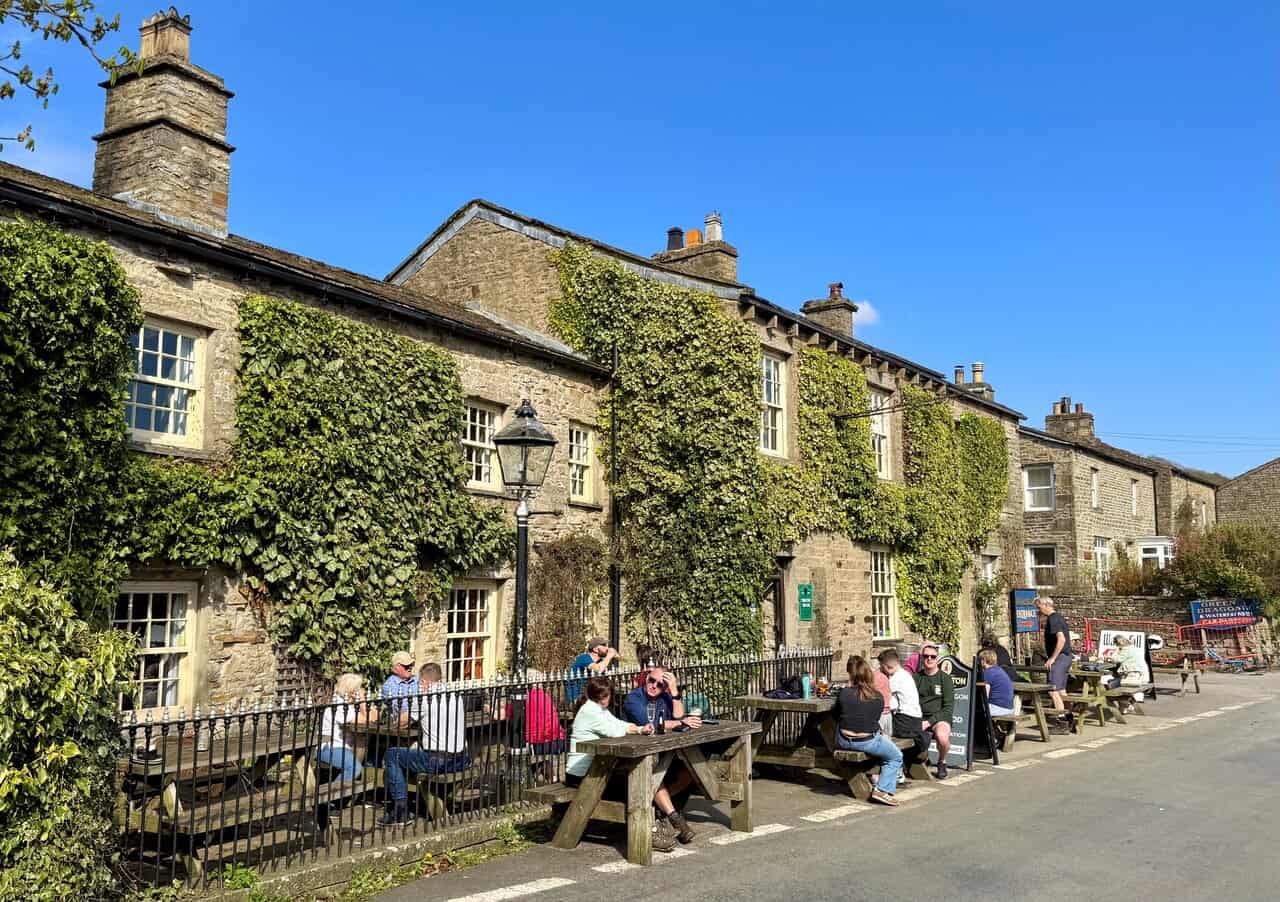 The Green Dragon Inn at Hardraw on a sunny day, with people sitting outside enjoying the warm weather.
