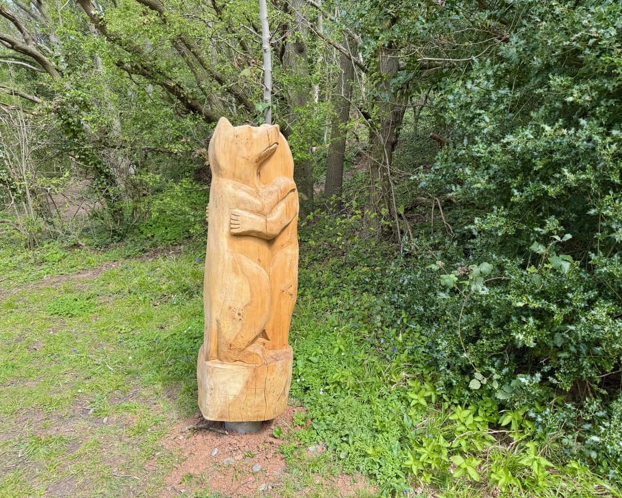 Two bears carved from a single trunk stand beside the woodland path.