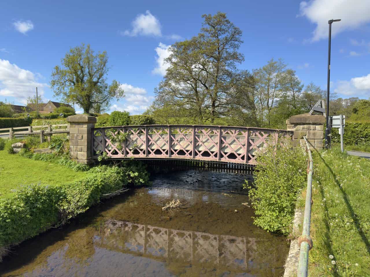 A handsome iron footbridge with decorative lattice ironwork spans the River Leven near Station Road on the Great Ayton walk.