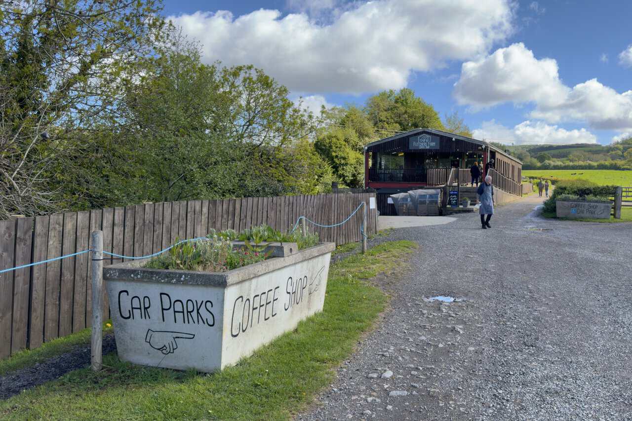 Fletcher’s Farm Coffee Shop sits in a large wooden building beside the track on the Great Ayton walk, with a painted sign pointing visitors towards the car park and café.