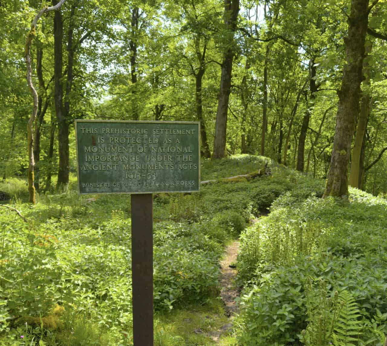 A weathered green plaque marking the prehistoric Iron Age settlement in Grass Wood Nature Reserve near Grassington.