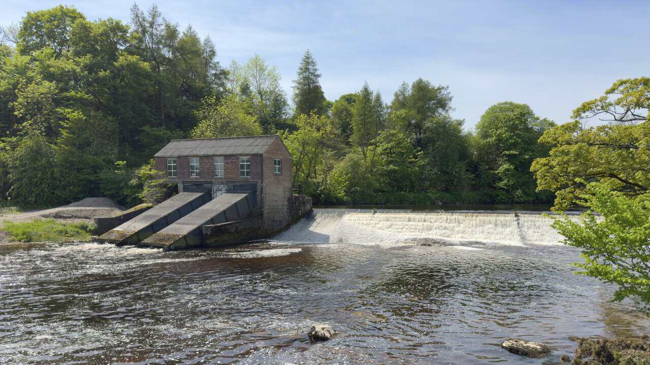 Linton Falls Hydro, a small red-brick hydroelectric station with sloping turbine channels beside the upper weir on the River Wharfe.