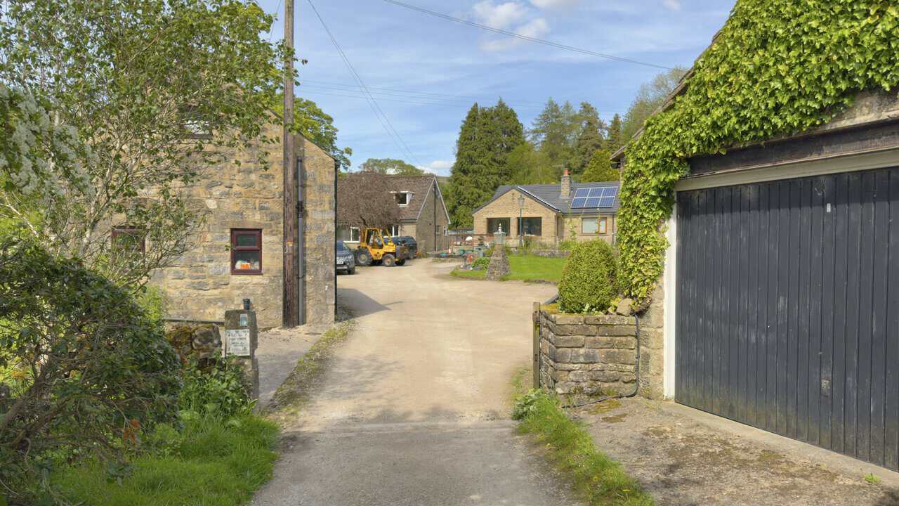 Public footpath from Mill Lane running down a driveway between two stone houses, signposted to Hebden and Bank Top.