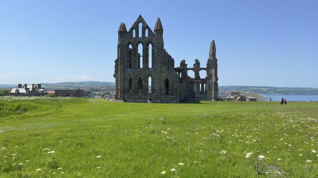 Whitby Abbey rises from a meadow of wildflowers, its Gothic ruins standing high above the North Sea.