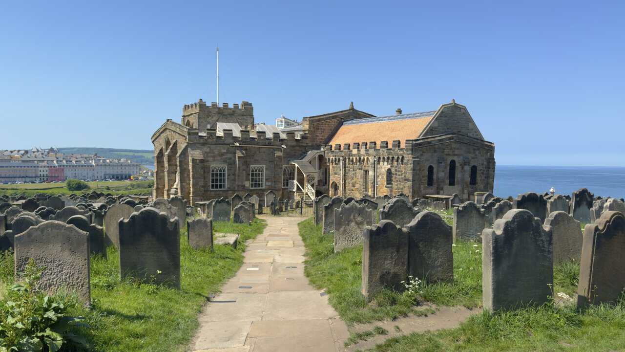 Weathered headstones lean in the churchyard of St Mary's Church, close to Whitby Abbey and overlooking the coast.