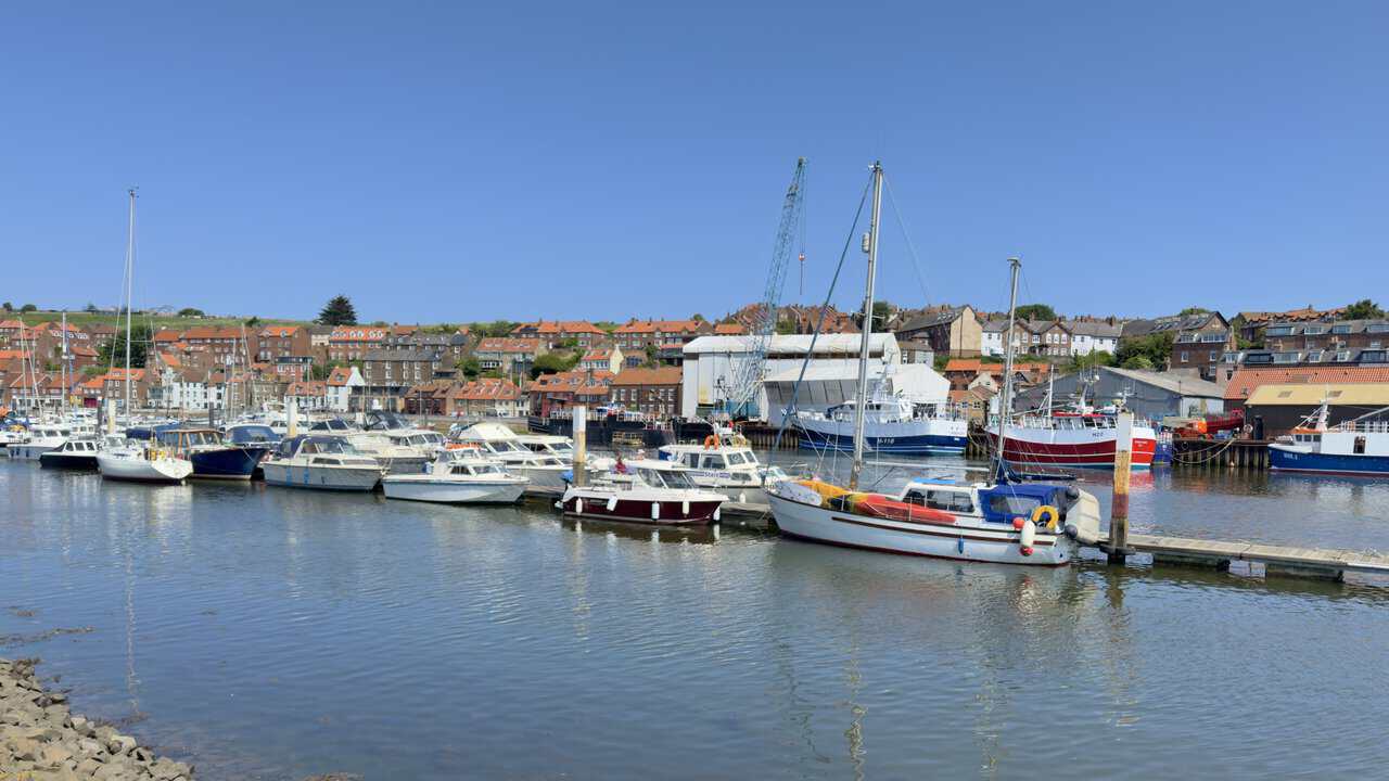 Boats line Whitby Marina on the River Esk, with the town rising behind the waterfront.