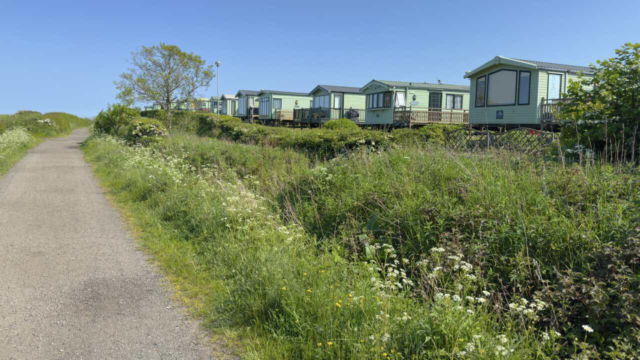 The Cinder Track passes beside Northcliffe and Seaview Holiday Parks, with caravans lined behind the hedge.