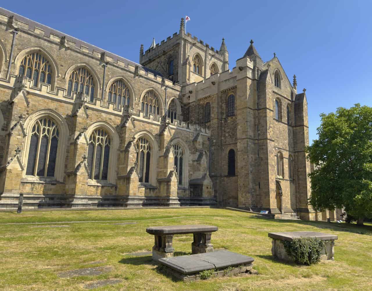 Weathered chest tombs in Ripon Cathedral churchyard, with the cathedral’s long windows and central tower beyond.