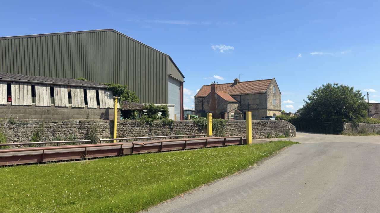 Whitcliffe Hall Farm near Ripon, with farm buildings, a stone farmhouse and a tractor in the yard.