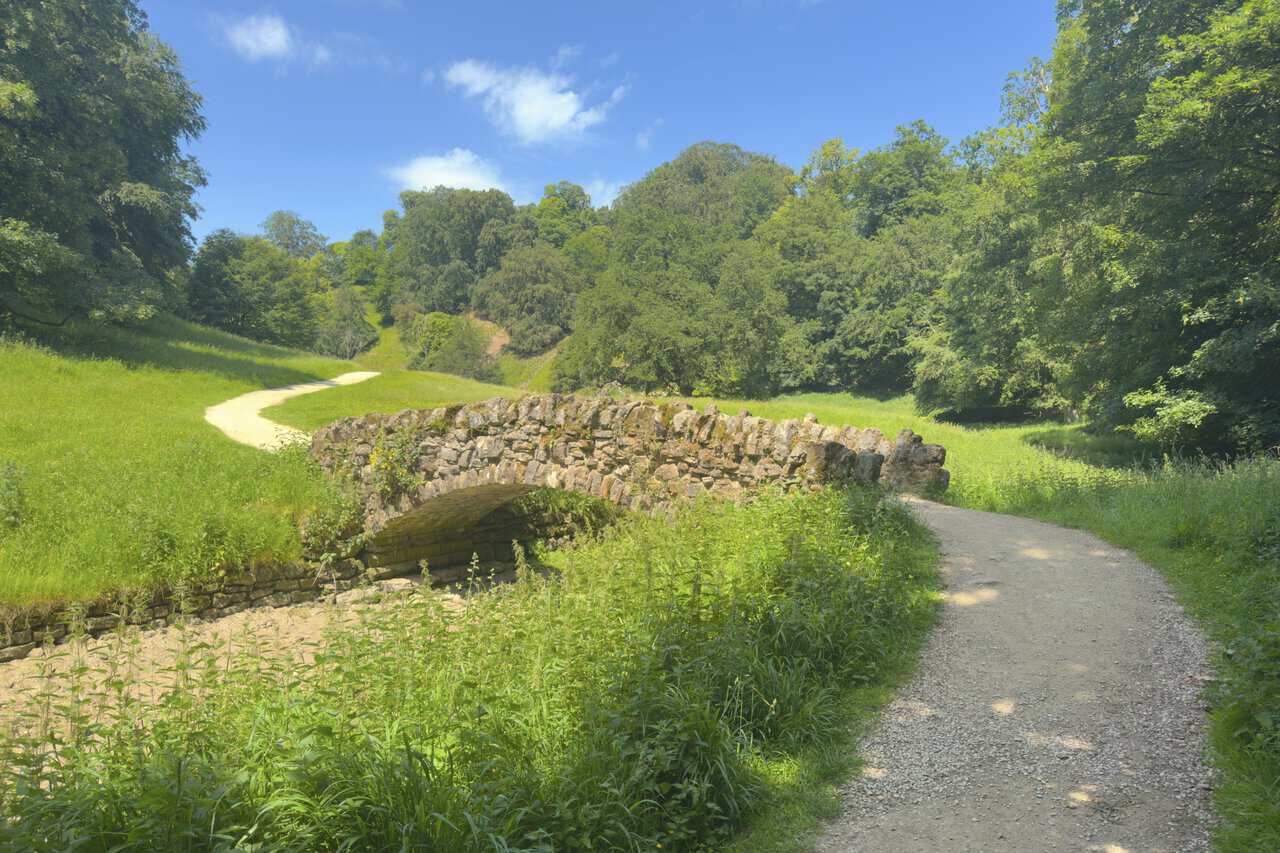 A narrow stone bridge over the River Skell in Seven Bridges Valley, Studley Royal Deer Park.