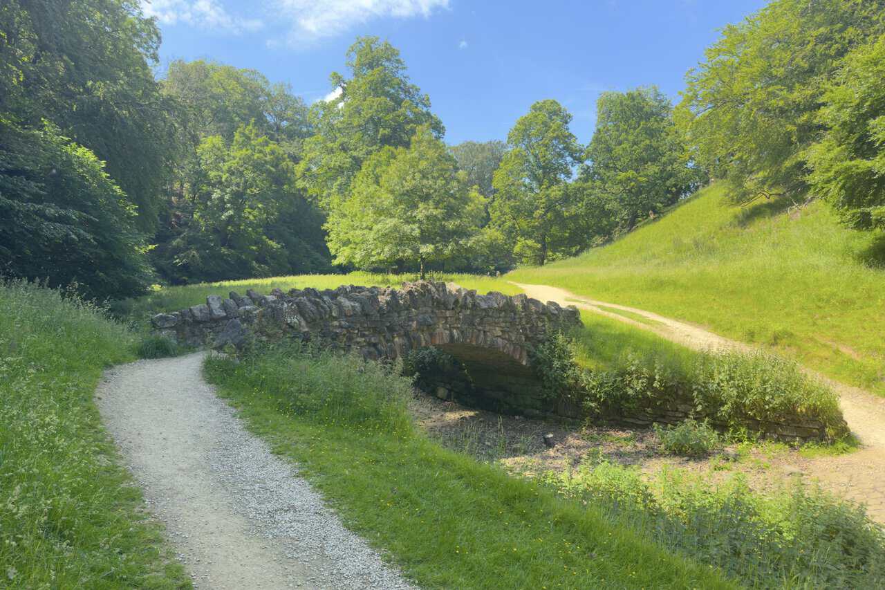 An old rough-stone arched bridge crossing the River Skell on a Ripon walk through Seven Bridges Valley.