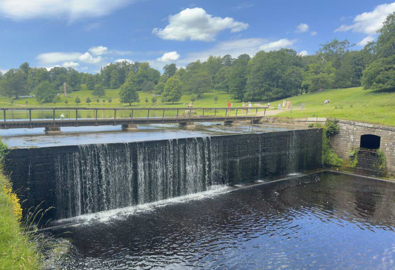 The weir at the northern end of The Lake in Studley Royal Deer Park, with St Mary’s Church visible through the trees.
