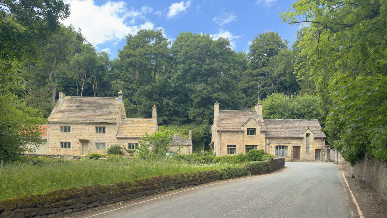 Stone cottages near the Fountains Abbey West Gate entrance on a Ripon walk, with gardens, walls and trees along the lane.