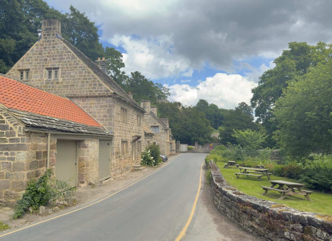 The lane beside the West Gate cottages at Fountains Abbey, curving between stone walls and gardens.