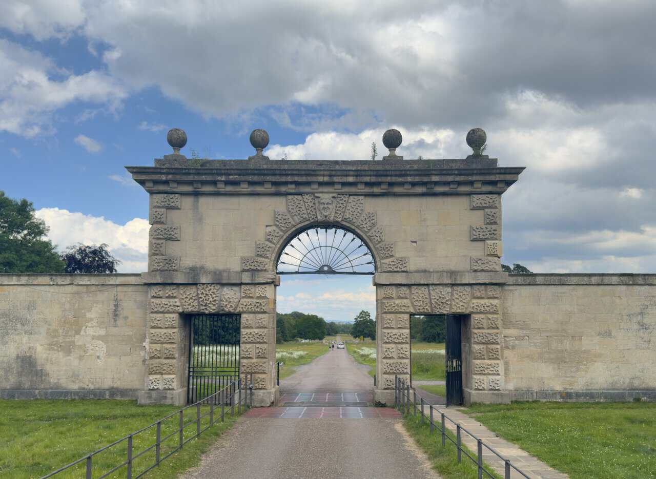 Close-up of Studley Great Gate, showing rusticated stonework, ironwork fanlight and carved keystone face.