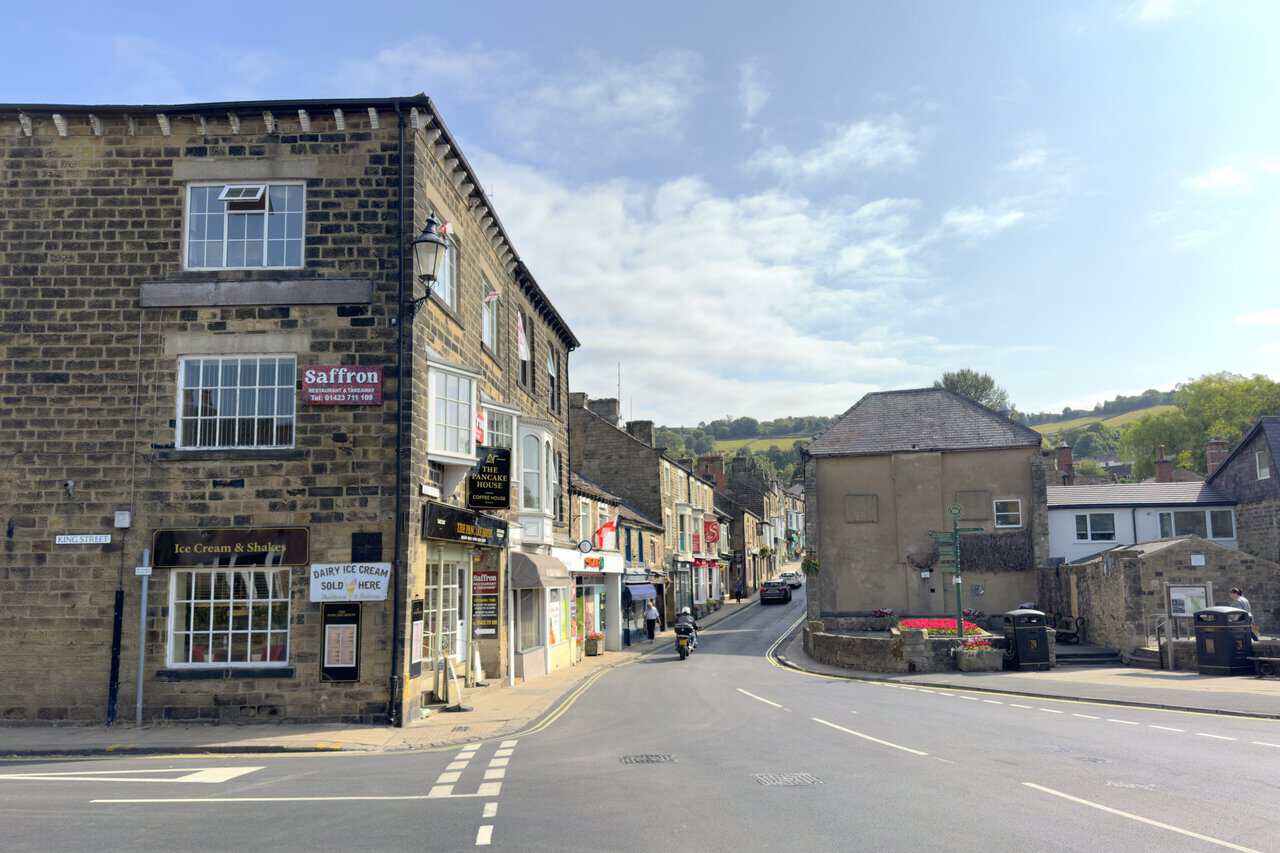 Stone-built shops and cafés lining the steep High Street in Pateley Bridge.