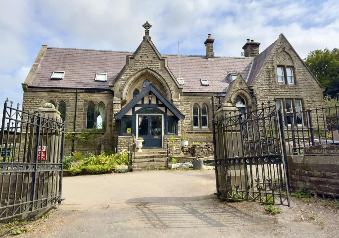 Open gates and old stone lodge at the entrance to Pateley Bridge Cemetery.