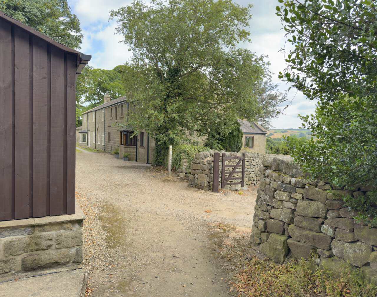 Wooden shed, stone cottages and a Nidderdale Way signpost pointing towards The Rocks.
