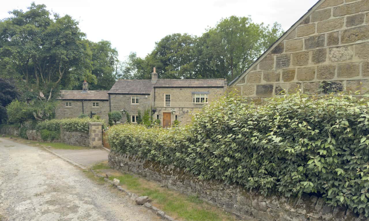 Stone houses near Little Mill and Knox Hall, with a footbridge crossing the beck.