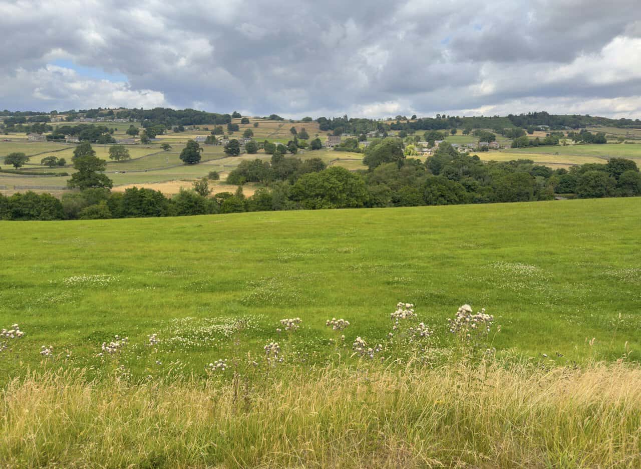 Wide valley views from the Brimham Rocks walk near Harewell Hall, with fields and farmsteads rising towards the moors.