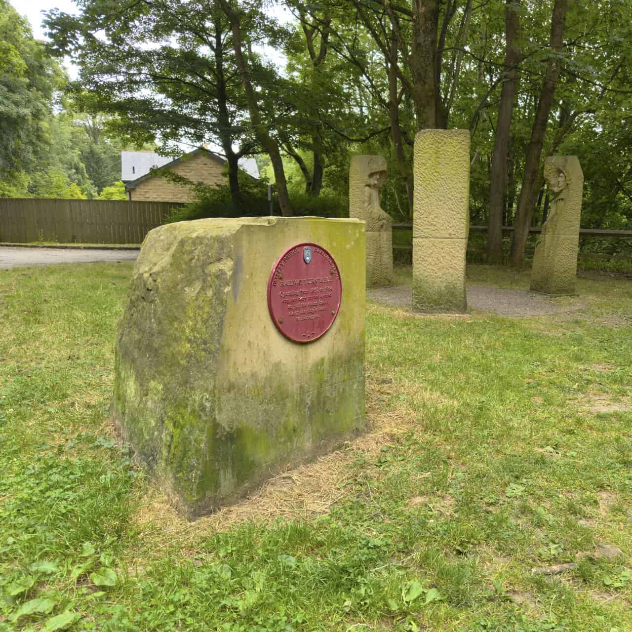 Heritage Trail plaque marking the former Pateley Bridge railway turntable beside the Pillars Past sculptures.