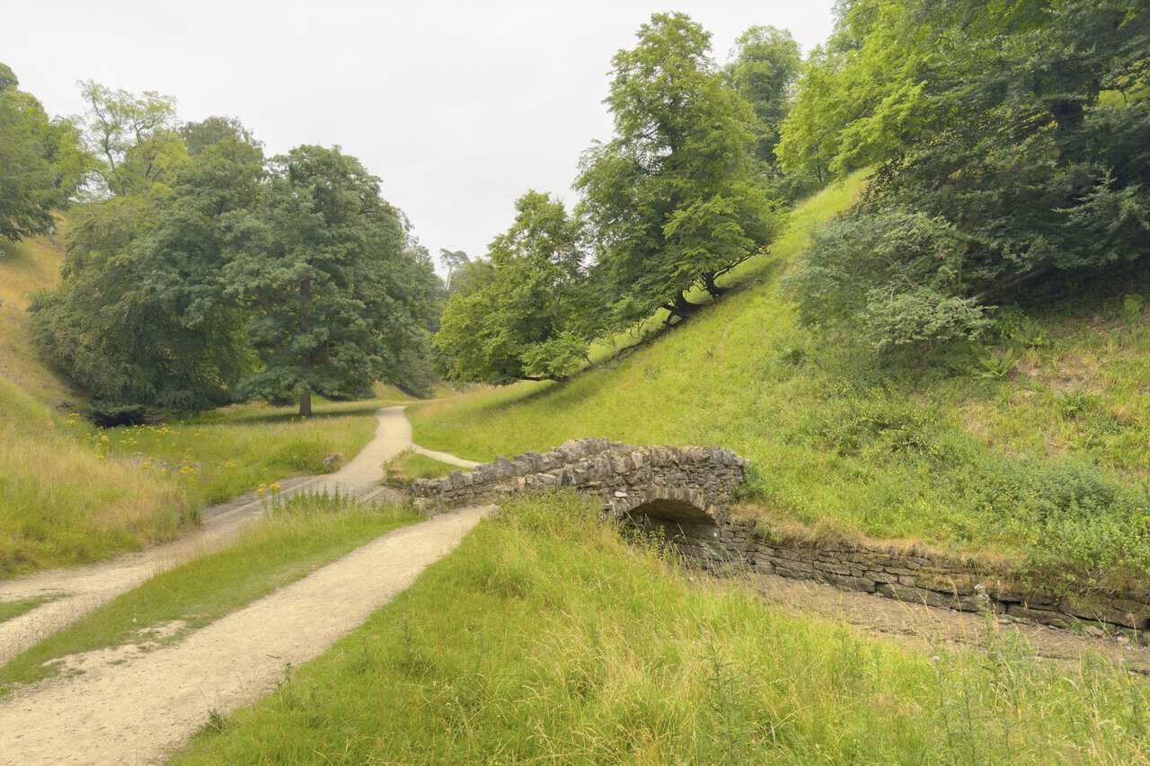 The fourth arched bridge tucked against the green flank of the valley, the path following the meandering Skell.