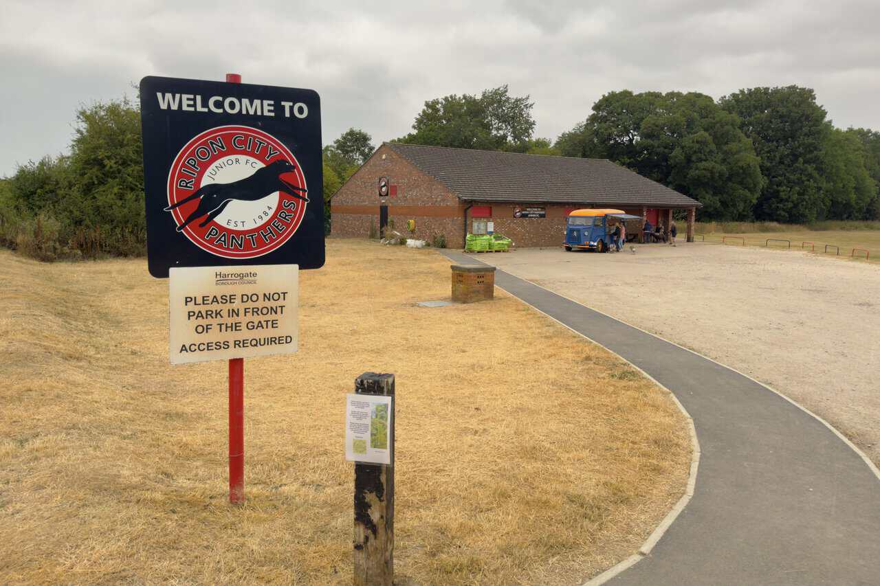 The welcome sign and brick clubhouse of Ripon City Panthers Junior Football Club, with a vintage coffee van alongside.