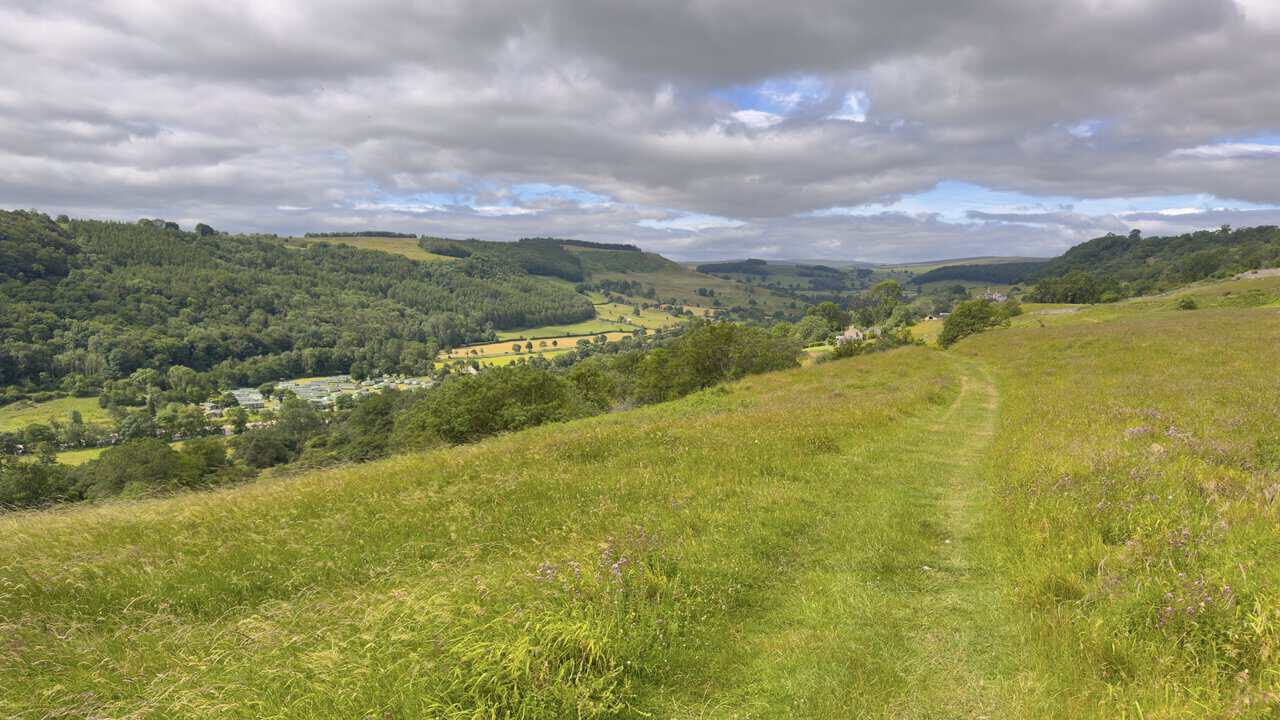 Swale View Caravan Park seen from the Richmond walk, set among trees in the valley below rolling fields and woodland.