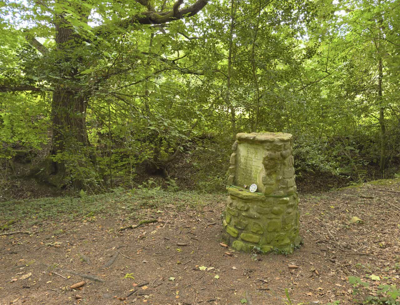 Small stone memorial in Whitcliffe Woods dedicated to Jane, her dogs and friends, with painted pebbles on its ledge.