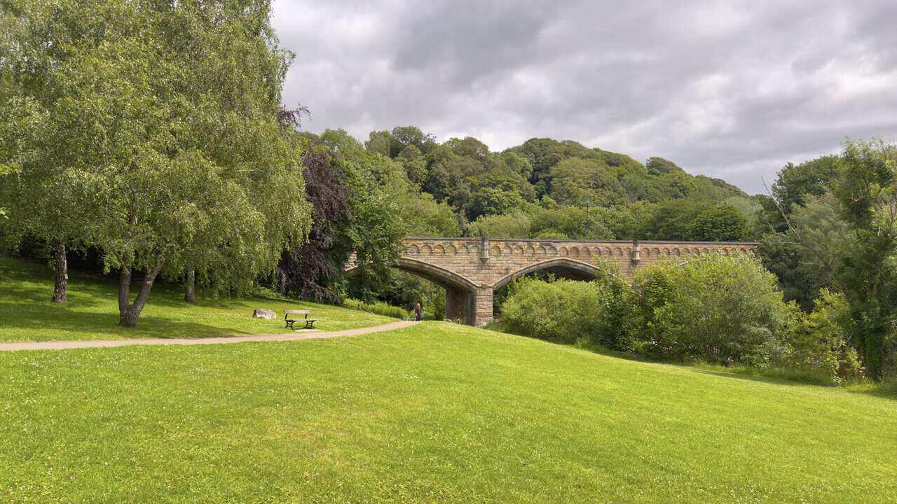 The Batts on the Richmond walk, with open riverside parkland, historic millstones and Mercury Bridge spanning the Swale.