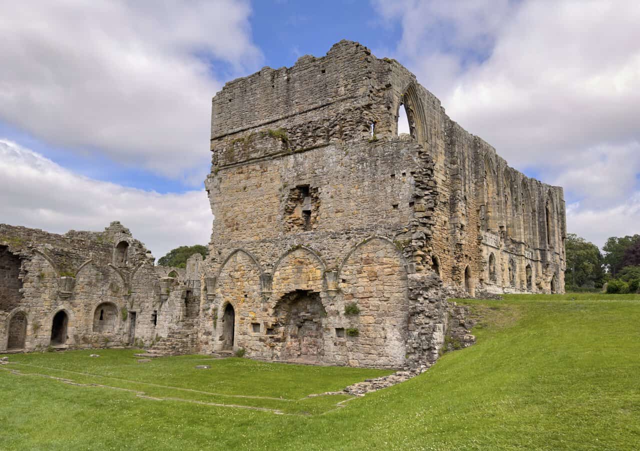 Stone walls and grassy foundations inside Easby Abbey, showing the scale of the former monastic buildings.