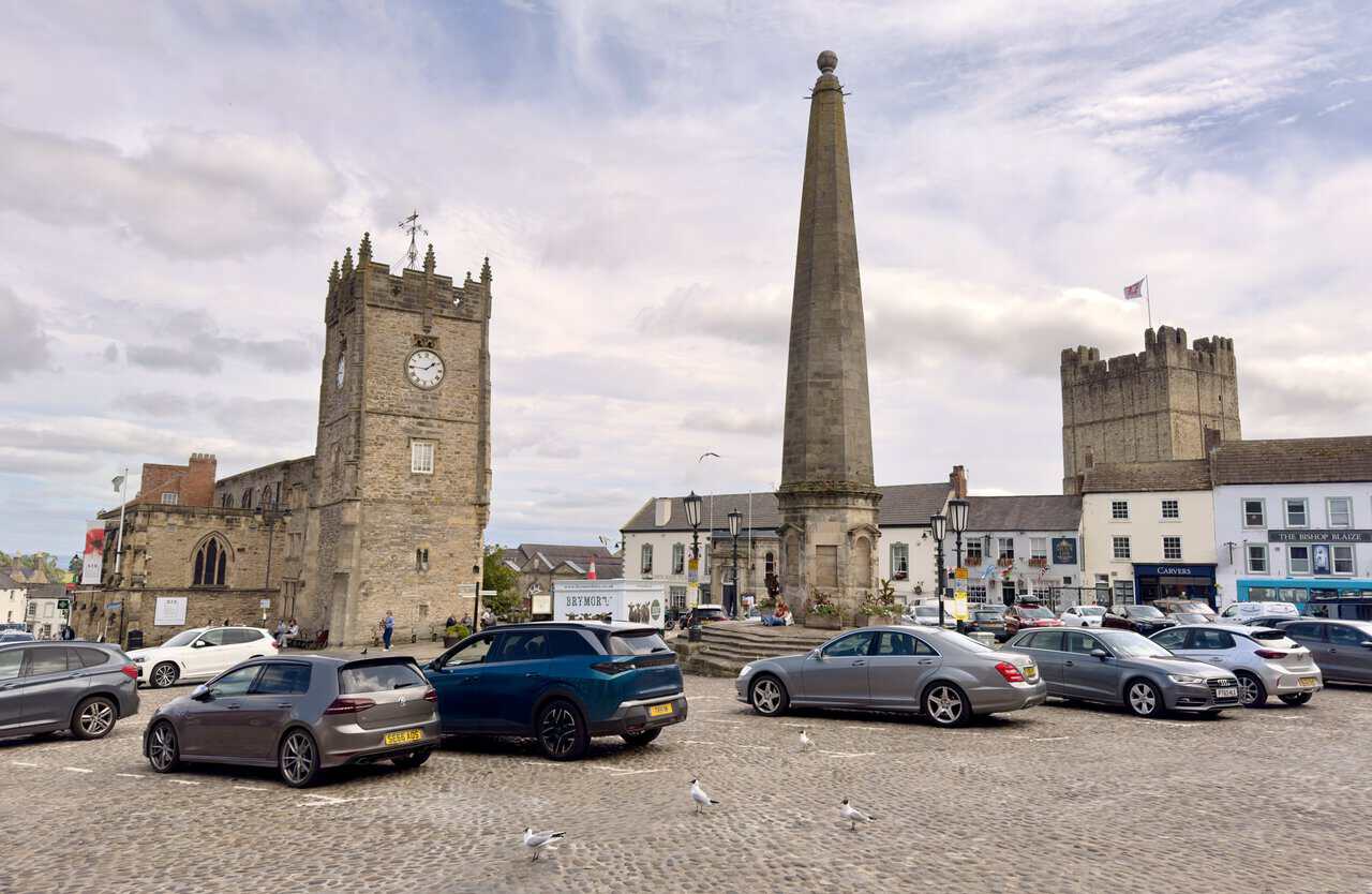 Richmond Market Place, with the obelisk, Holy Trinity clock tower, shops, cafés and castle keep above the rooftops.