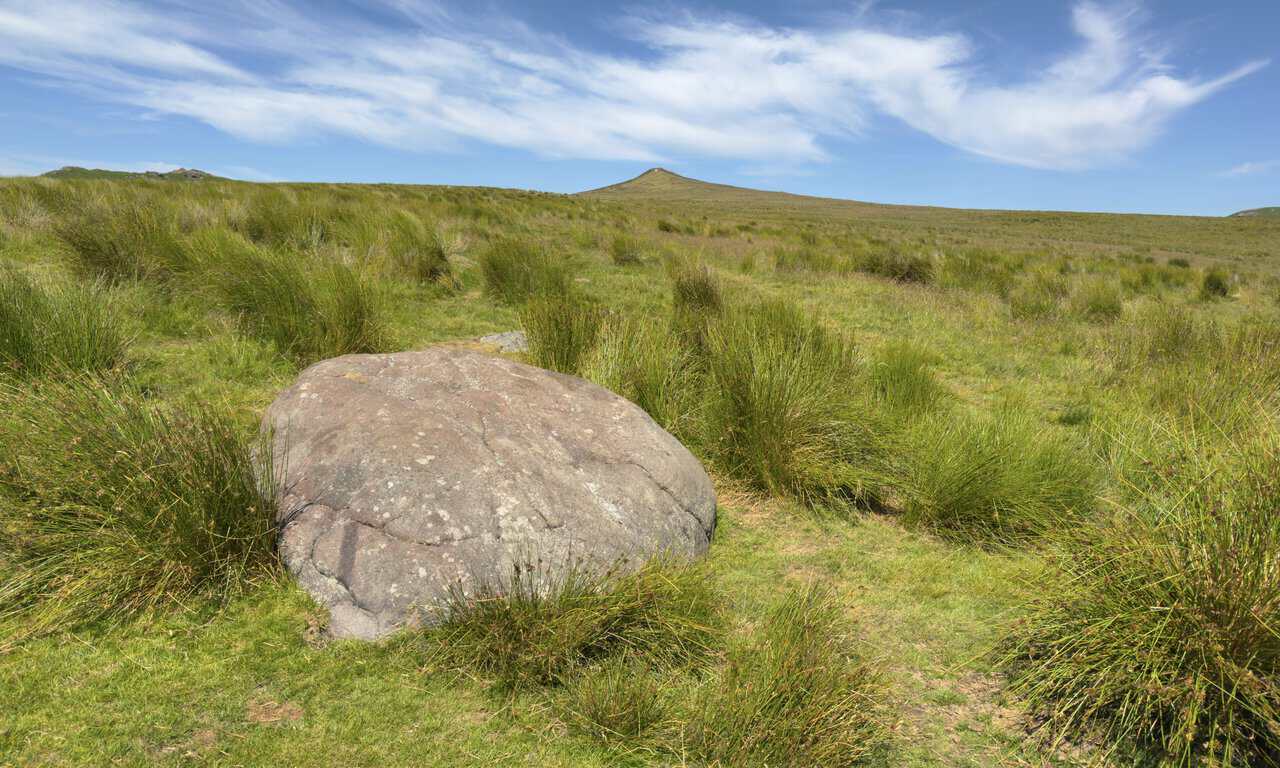 Large weathered boulder beside the Dales High Way on Flasby Fell, with Sharp Haw beyond.