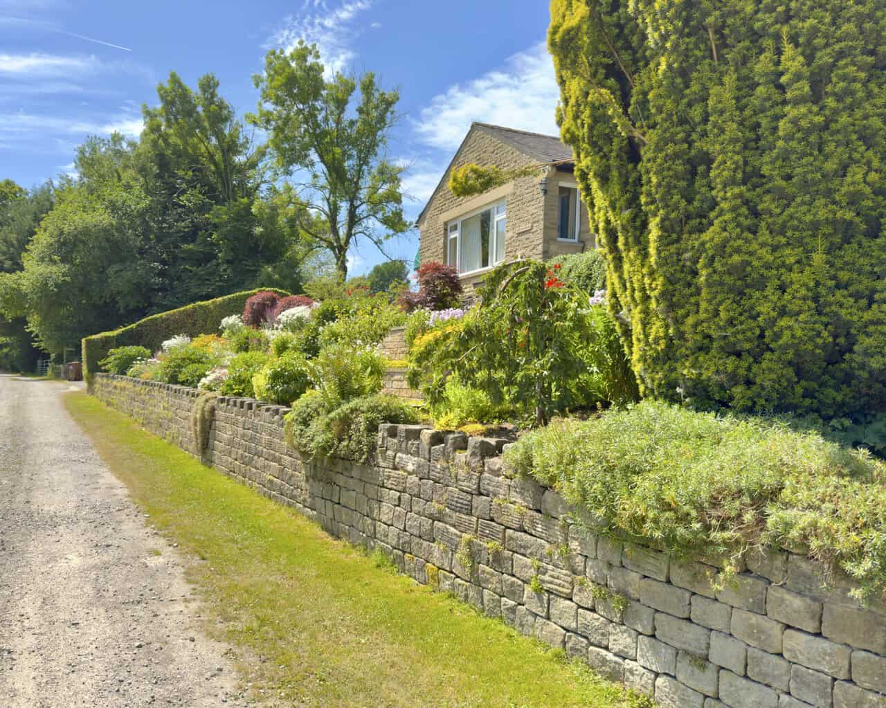 Track past Tenter Ghyll bungalow in Flasby, its terraced garden banked behind a low stone wall.