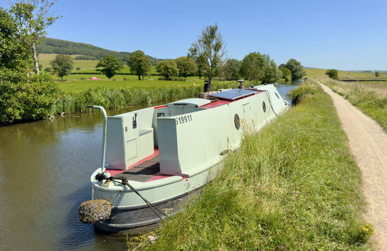 Narrowboat moored on the Leeds and Liverpool Canal with a solar panel on its roof.