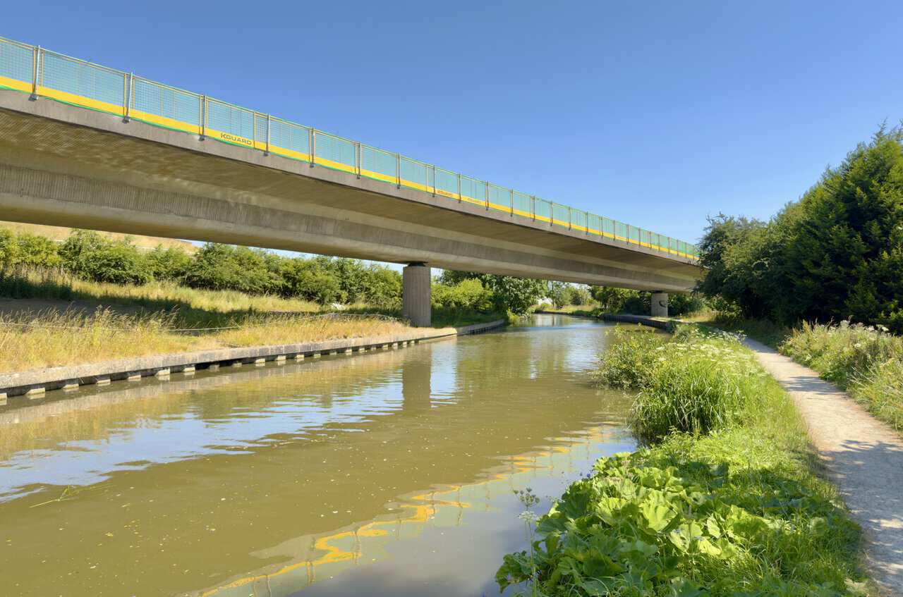 Concrete bridge carrying the A629 over the Leeds and Liverpool Canal, reflected in the water.
