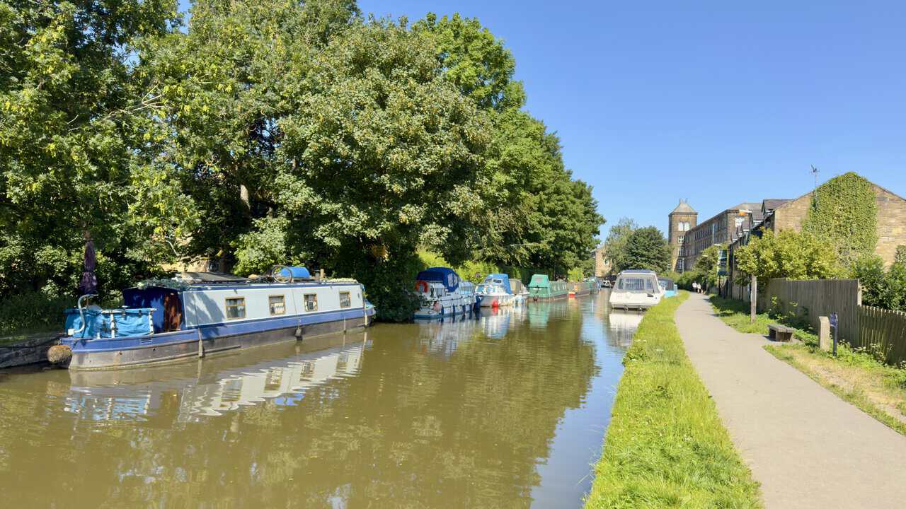 Moored boats and a mill building on the Leeds and Liverpool Canal on the approach to Skipton.