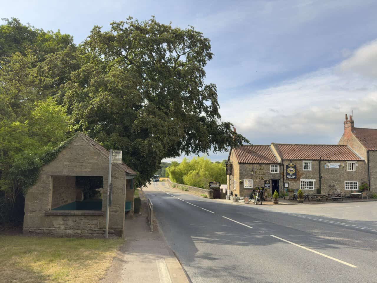 The Bull Inn and an old stone bus shelter beside the road leading to Tanfield Bridge at the start of the West Tanfield walk.