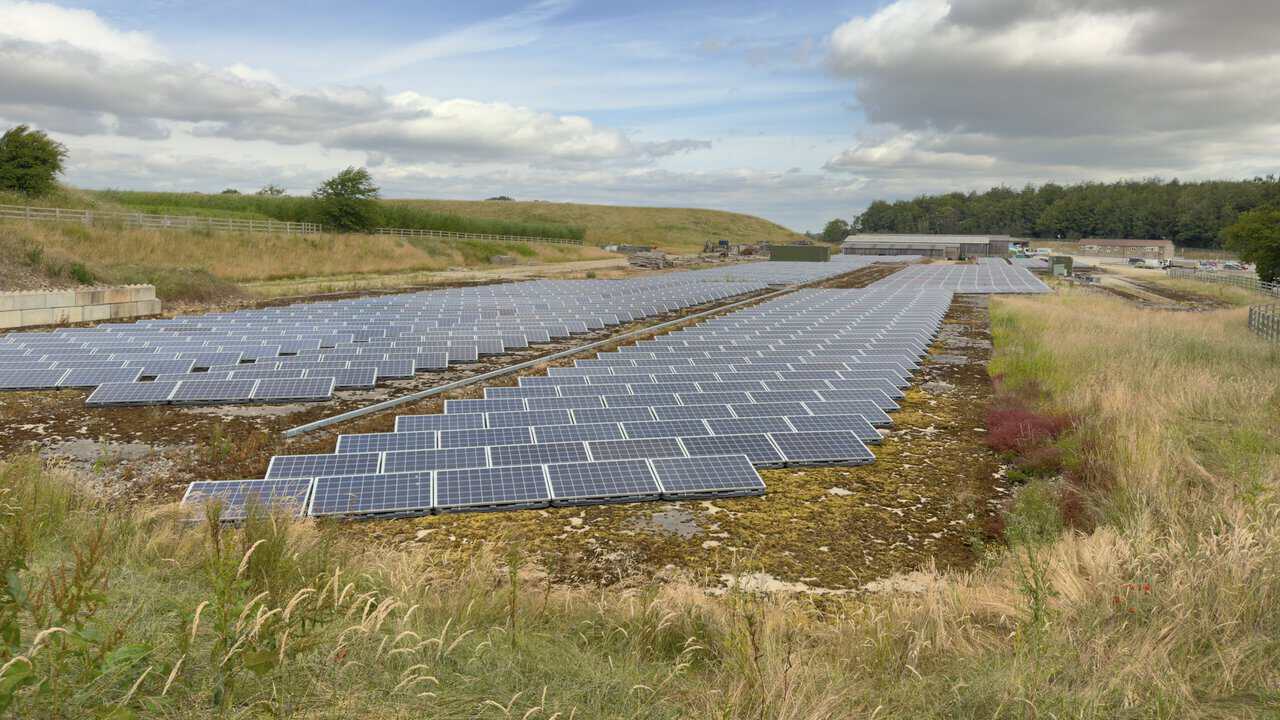 Rows of solar panels at Lightwater Quarries with industrial sheds, quarry buildings and working yards behind them.