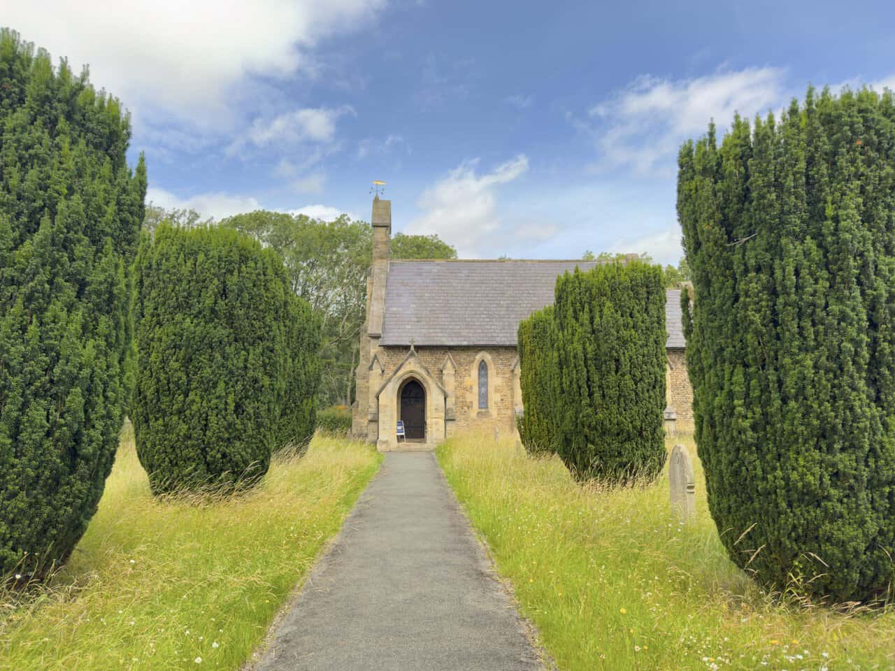 St John the Evangelist Church in Mickley, a historic landmark on the West Tanfield walk, approached between clipped yew trees.