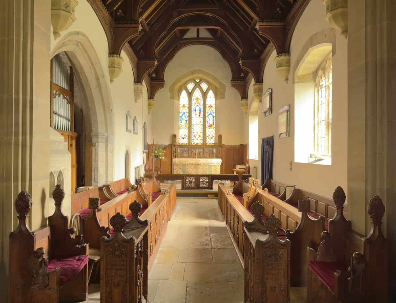Interior of St Nicholas’s Church on the West Tanfield walk, with carved pews, a timber roof, stone flooring and stained glass.