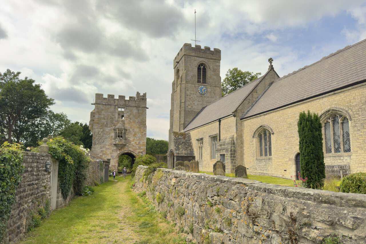 Marmion Tower standing at the end of a walled grassy lane beside St Nicholas’s Church in West Tanfield.