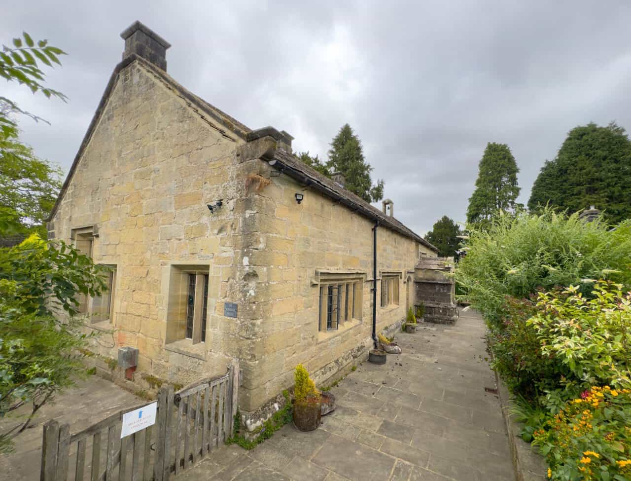 Exterior of Bewerley Grange Chapel, a long, low gritstone building with a stone slate roof and a flagged path alongside.