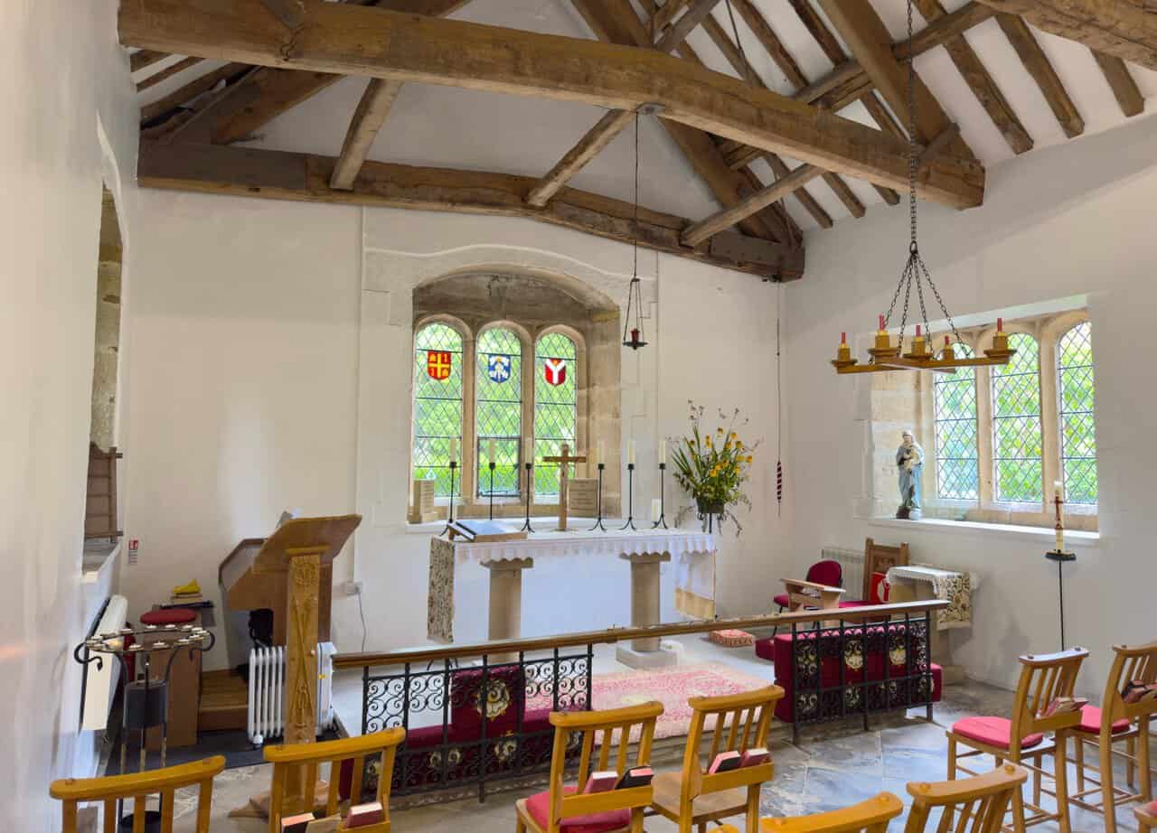 Interior of Bewerley Grange Chapel on the Yorke's Folly walk, showing the altar beneath a stained glass window and old timber roof beams.