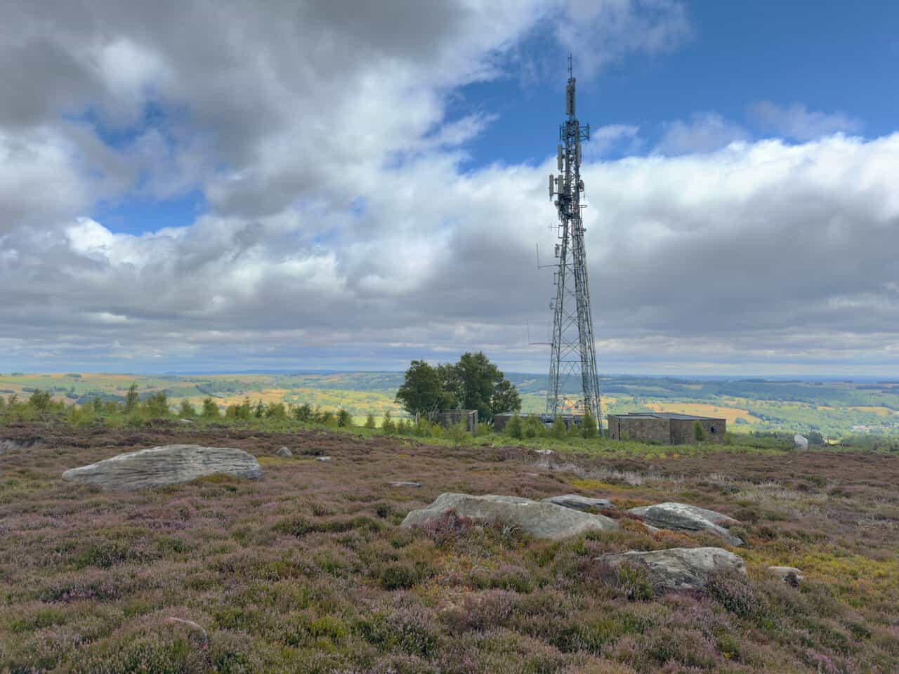 The EE telecommunications mast on the moor, standing beside a low stone building among the heather.