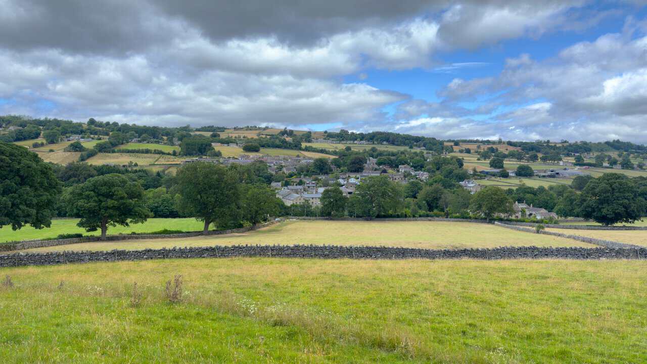 View over the rooftops of Glasshouses, with the church tower and wooded hills of Nidderdale behind.