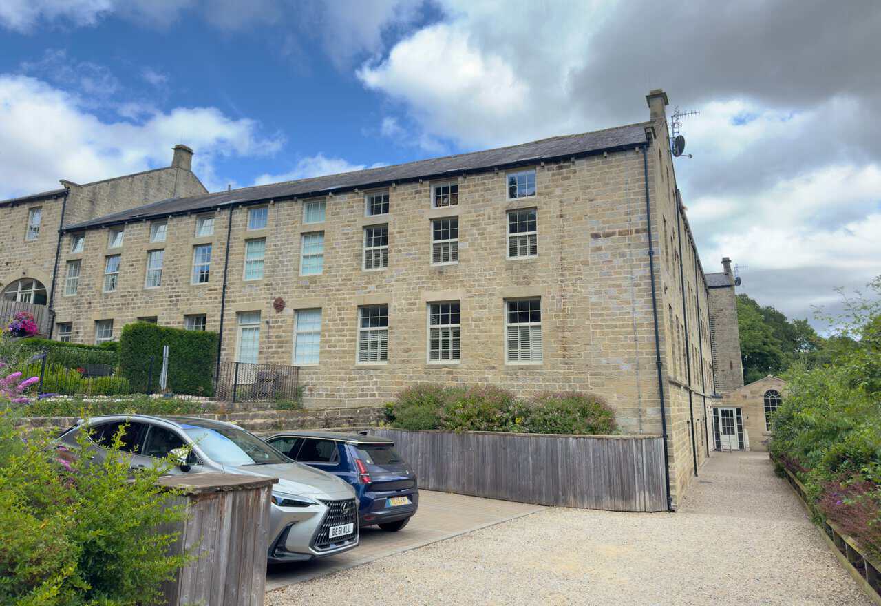Glasshouses Mill, a large stone mill beside the River Nidd, now converted into homes.