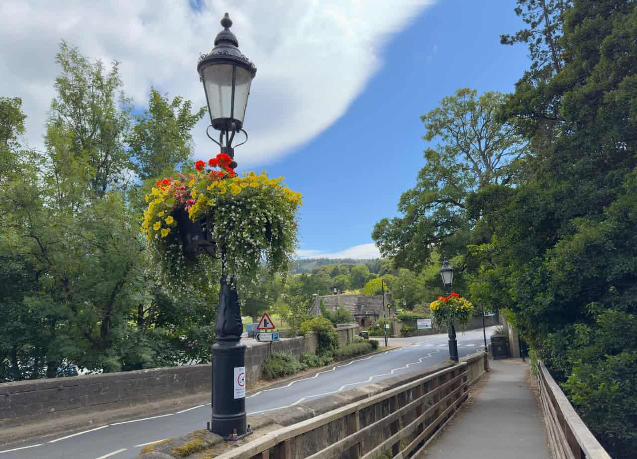 The bridge over the River Nidd at Pateley Bridge on the Yorke's Folly walk, with a cast-iron lamp post and hanging baskets of flowers.
