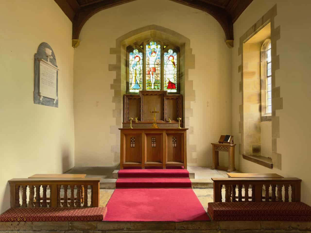 The chancel of St Martin's Church with stained glass window above the wooden altar.